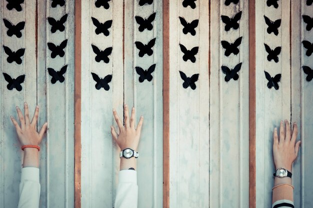 Des mains coupées de gens atteignant des peintures de papillons sur le mur