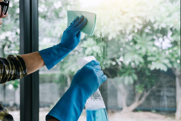 Des mains coupées d'un homme nettoyant une fenêtre de verre.