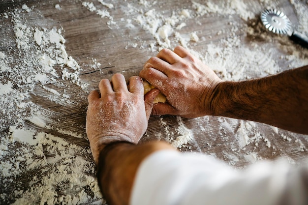 Des mains coupées d'un homme préparant de la pâte sur la table