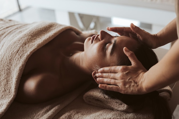 Des mains coupées d'une masseuse donnant un massage à une femme au spa