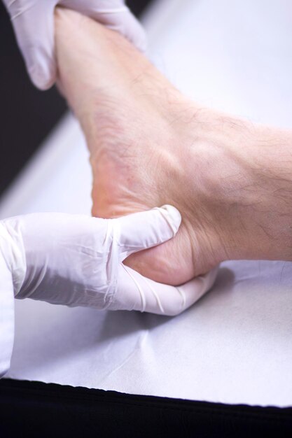 Photo des mains coupées d'un médecin examinant un pied