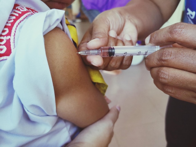 Photo des mains coupées d'un médecin vaccinant un enfant à l'hôpital