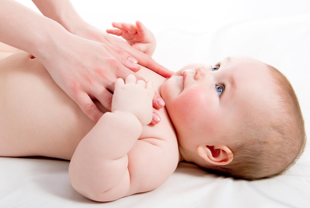 Des mains coupées d'une mère avec sa fille allongée sur le lit.