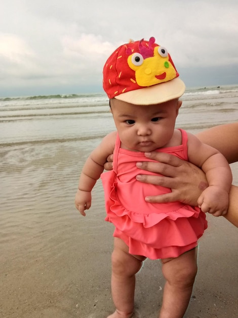 Photo des mains coupées d'une mère tenant sa fille sur la plage