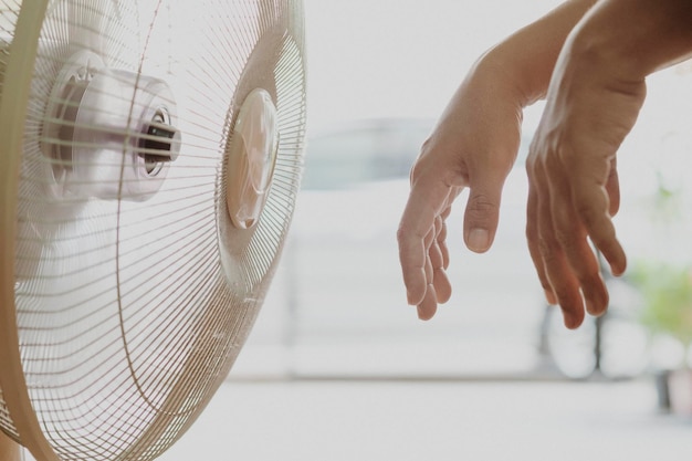 Photo des mains coupées par un ventilateur électrique à la maison.