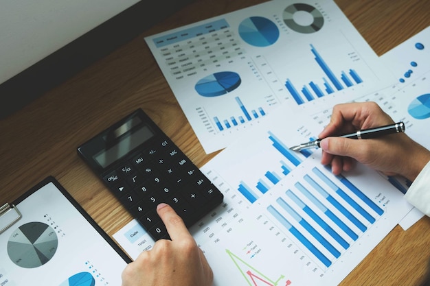 Photo des mains coupées d'une personne avec une calculatrice analysant des graphiques sur un bureau