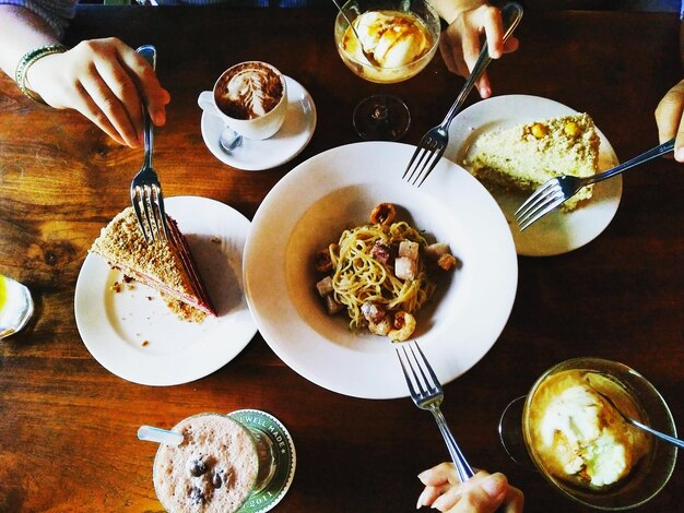 Des mains coupées d'une personne prenant le petit déjeuner servi sur la table