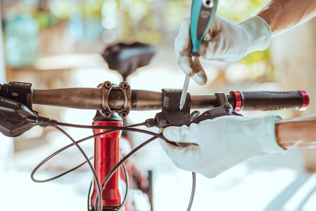 Photo des mains coupées d'une personne réparant un vélo