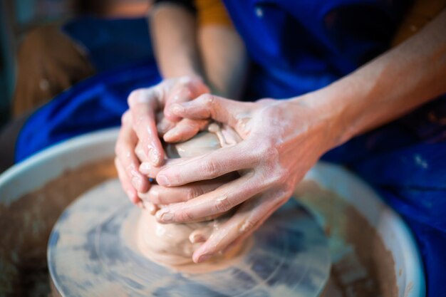 Mains coupées de potiers travaillant dans un atelier de poterie