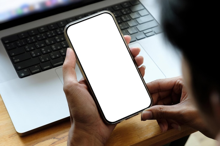 Photo des mains coupées avec un téléphone portable sur la table.