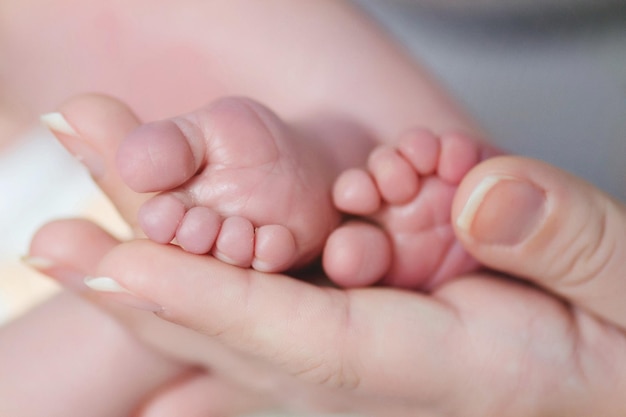 Des mains coupées tenant les pieds d'un bébé.