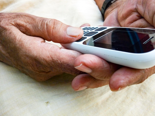 Photo des mains coupées en utilisant un téléphone portable à la maison