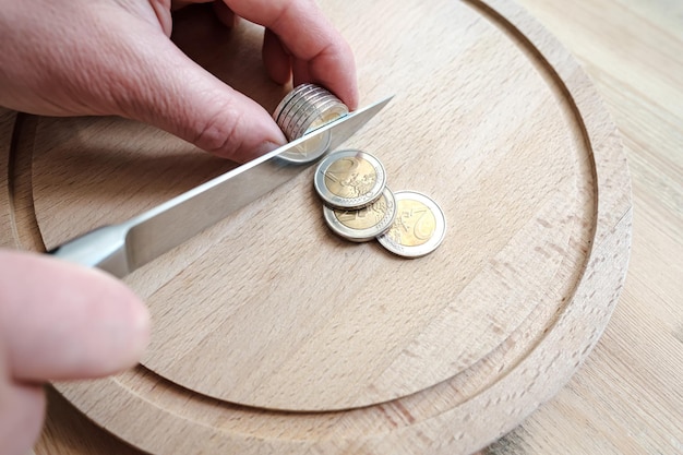 Les mains coupent les pièces en euros comme des morceaux de nourriture sur une planche à découper Concept de fraude fiscale ou de profit