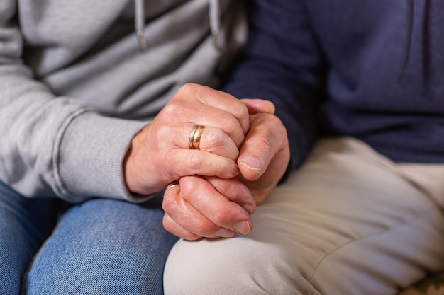 Mains d'un couple de personnes âgées tenant ensemble les soins et le soutien