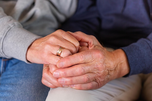 Mains d'un couple de personnes âgées tenant ensemble les soins et le soutien