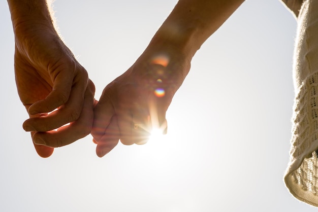 Photo mains de couple tenant avec les rayons du soleil