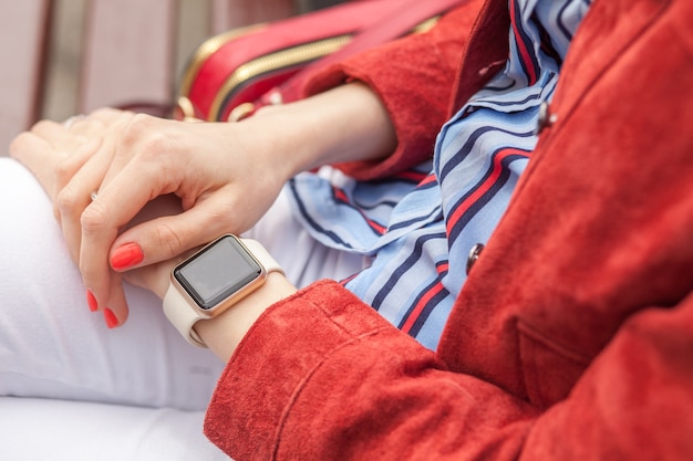 Mains croisées féminines élégantes avec montre intelligente avec écran blanc en plein air