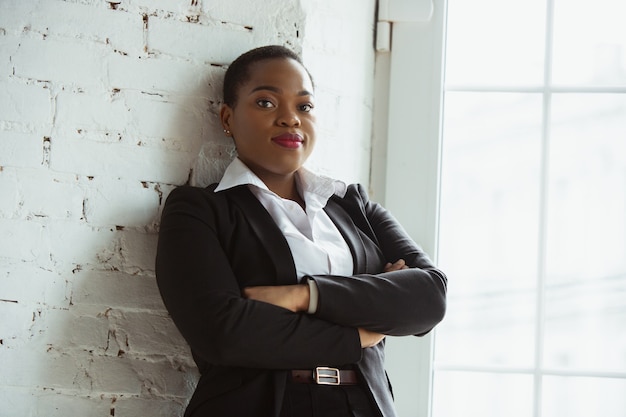 Les mains croisées. Femme d'affaires afro-américaine en tenue de bureau souriante, a l'air confiante et heureuse, occupée. Concept de finance, d'entreprise, d'égalité et de droits de l'homme. Belle jeune femme modèle, réussie.