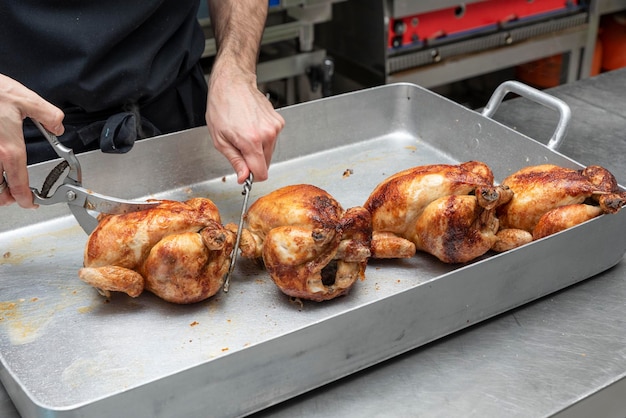 Photo les mains d'un cuisinier méconnaissable coupant en tranches le poulet rôti