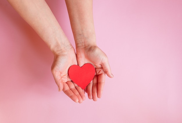 Les mains d'une dame tenant un coeur sur un mur rose, Saint Valentin