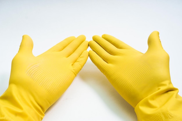 Mains dans des gants en caoutchouc jaune sur fond blanc