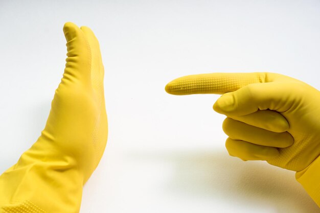 Mains dans des gants en caoutchouc jaune sur fond blanc