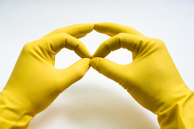 Photo mains dans des gants en caoutchouc jaune sur fond blanc