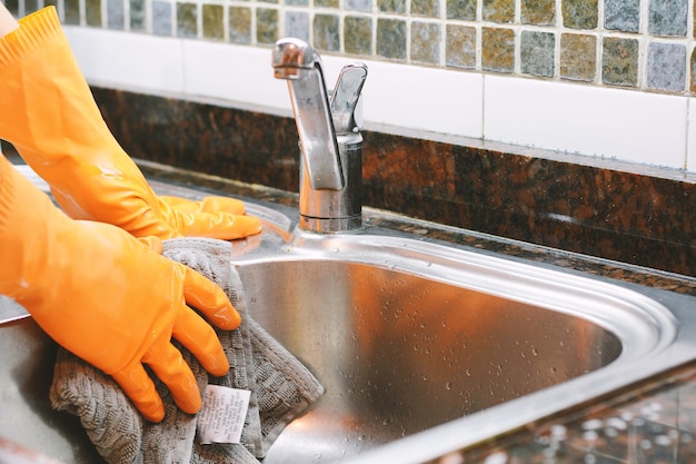 Mains dans des gants en caoutchouc, laver la vaisselle à la cuillère