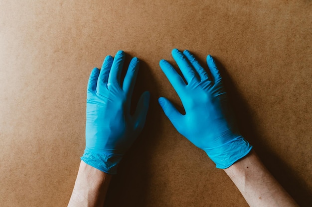 Mains dans des gants de protection en caoutchouc bleus sur fond beige Vue de dessus du concept de soins de santé et d'antivirus