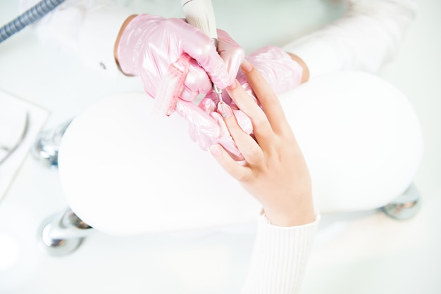 Les mains dans les gants se soucient des ongles des mains. Salon de beauté manucure.