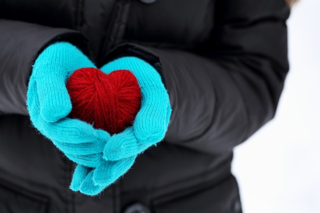 Mains dans des mitaines tricotées tenant un coeur rouge