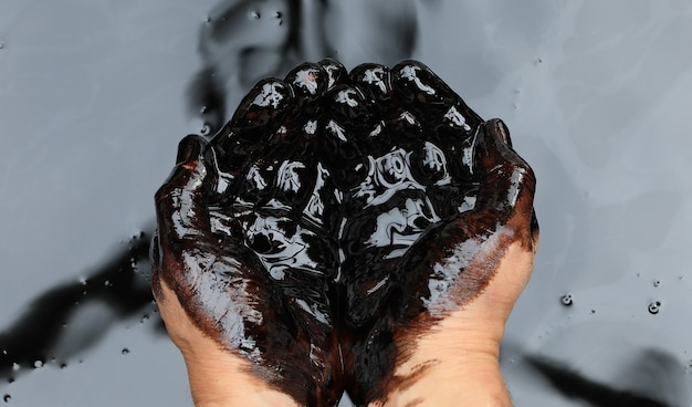 mains dans le pétrole brut noir