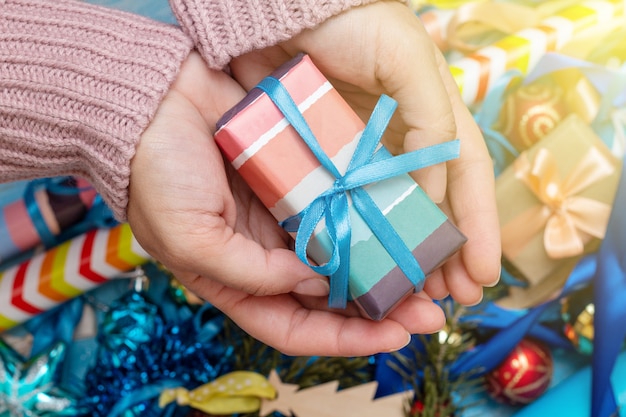 Mains dans un pull en tricot tenant la boîte cadeau présente. Concept de préparation de vacances de Noël.