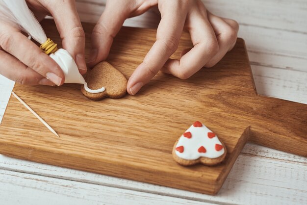 Mains décorant des biscuits en pain d'épice avec du glaçage