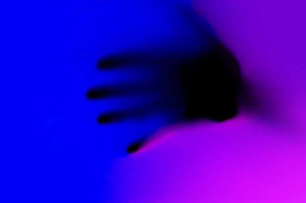 Mains en dégradé de néon bleu et rose derrière la surface blanche.