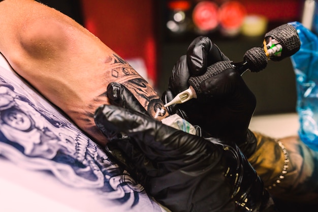 Photo mains dessinant avec un stylo de tatouage sur le bras