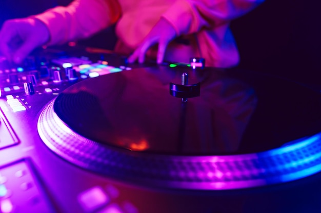 Les mains d'un DJ créant et régulant la musique sur le mixer de la console DJ lors d'un concert de club