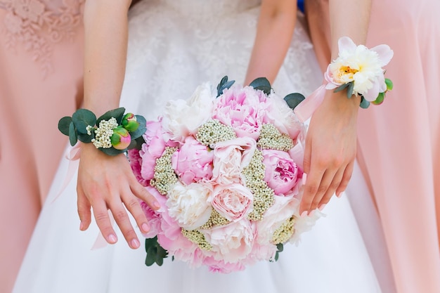 Mains douces des filles avec une belle manucure La mariée tient un bouquet de pivoines les filles ont une boutonnière à la main