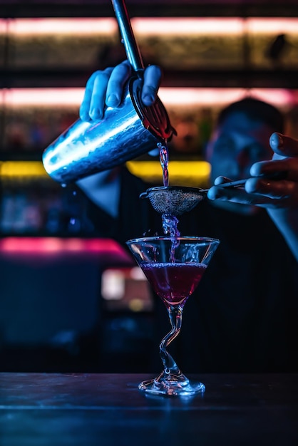 Les mains du barman versent du jus à travers un tamis dans un verre à cocktail rempli d'une boisson alcoolisée dans un restaurant Boisson gazeuse alcoolisée dans une discothèque Russie RostovonDon 19mars2022