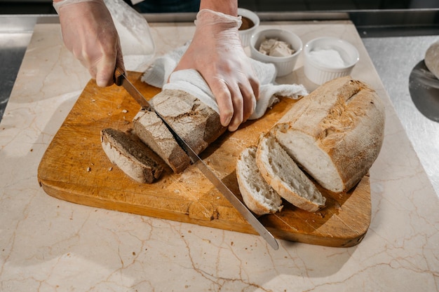 Les mains du chef masculin coupent le pain. Photo de haute qualité