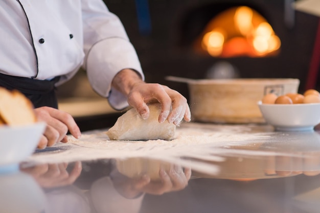 mains du chef préparant la pâte à pizza sur saupoudrée de gros plan de table de farine