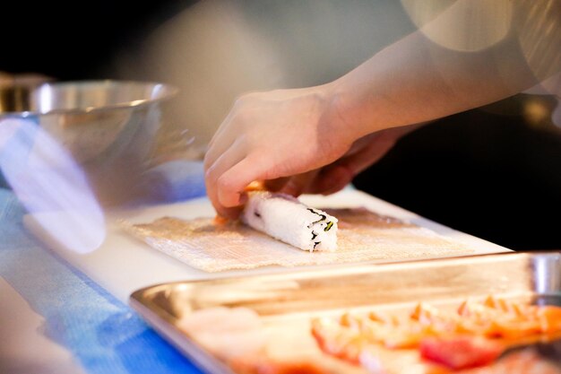 Les mains du chef préparent la nourriture japonaise, le chef prépare le sushi, la préparation du rouleau de sushi Maki.