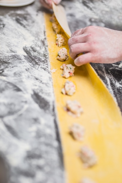 Les mains du chef préparent des raviolis de pâtes farcies à la cuisine italienne.