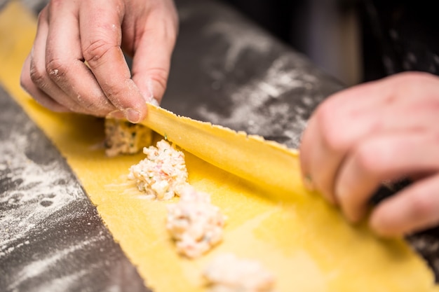 Les mains du chef préparent des raviolis de pâtes farcies à la cuisine italienne.