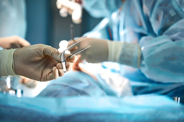 Les mains du chirurgien tiennent un outil opératoire dans la salle d'opération.