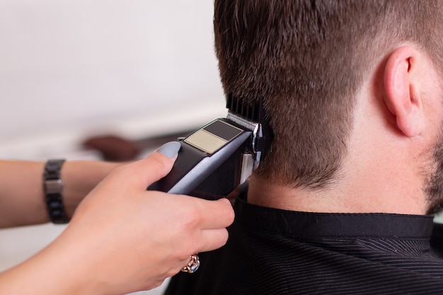 Les mains du coiffeur féminin faisant la coupe de cheveux