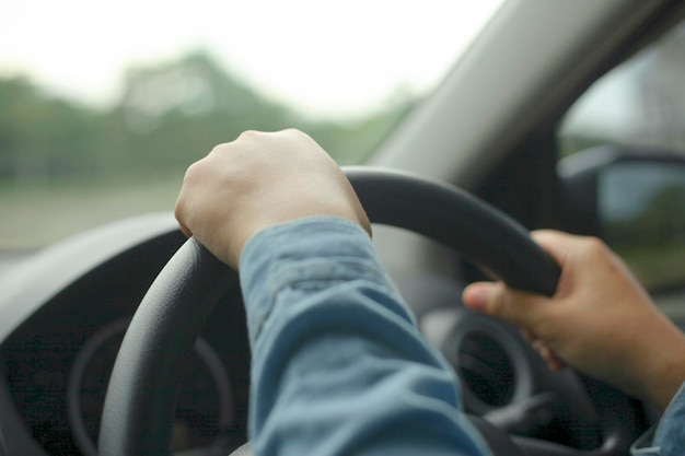 Les mains du conducteur sur le volant conduisant un concept de voiture en gros plan avec mise au point sélective