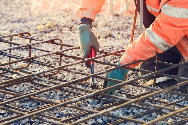 Les mains du constructeur fixant les barres de renfort en acier sur le chantier de construction