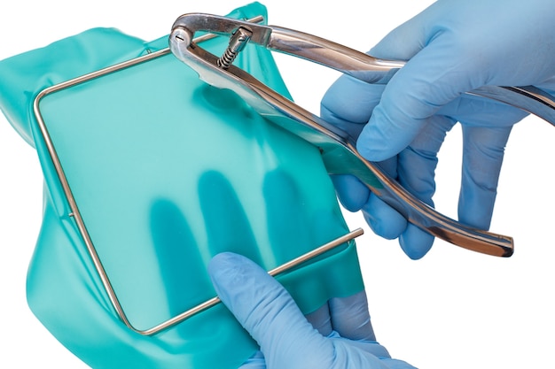 Les mains du dentiste dans des gants en latex avec poinçon dentaire, écharpe de batardeau et cadre en métal sur fond blanc isolé. Concept d'outils médicaux.
