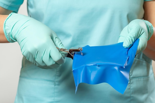 Photo les mains du dentiste dans des gants avec poinçon dentaire et écharpe batardeau